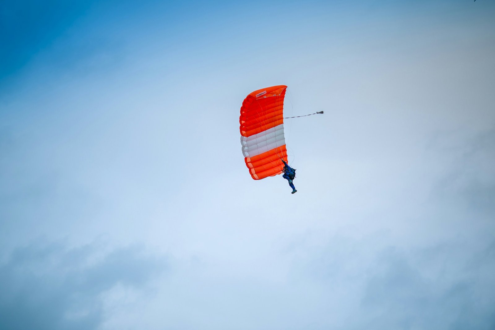 A person skydiving with arms and legs extended, floating against the backdrop of the sky