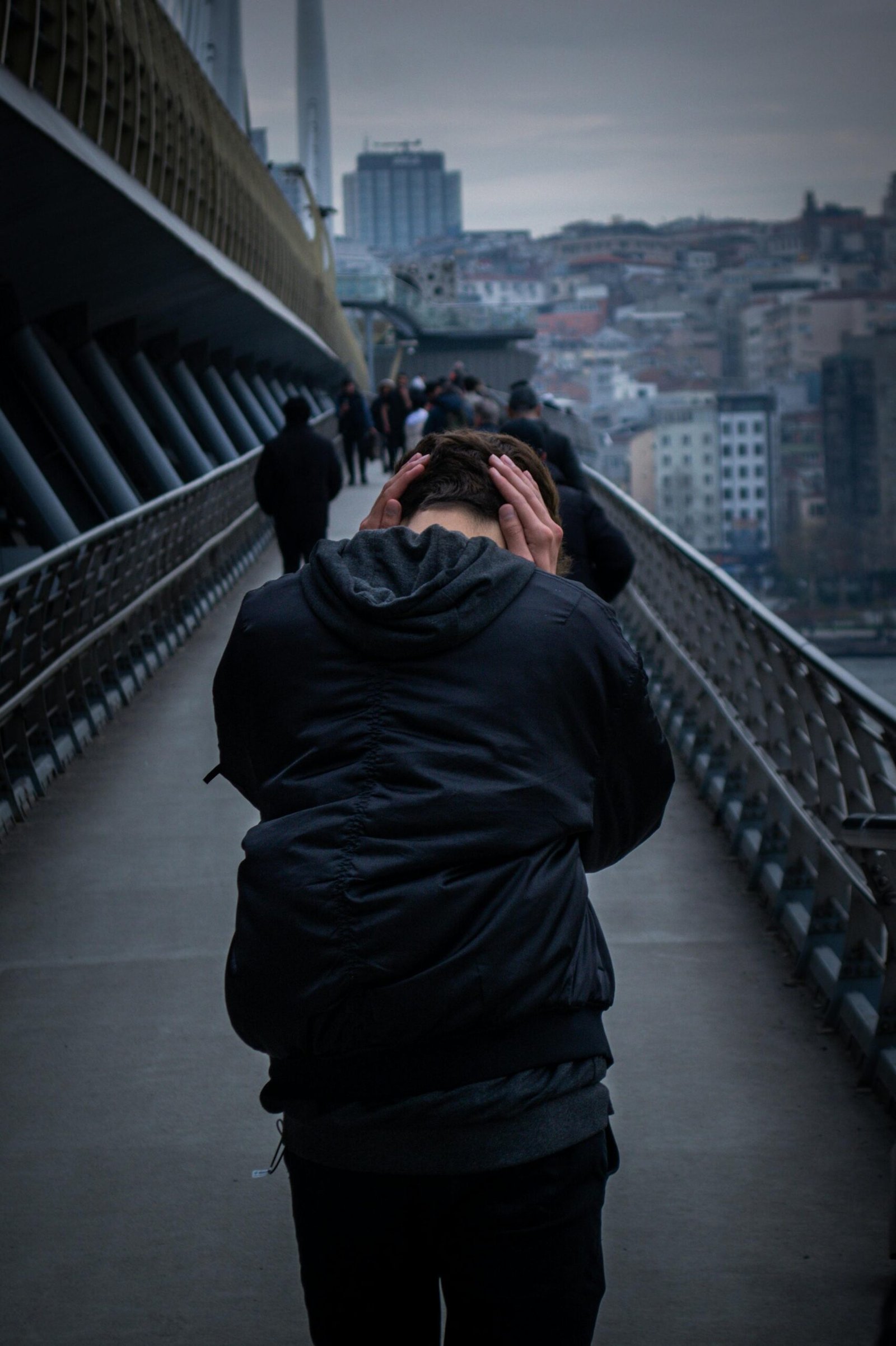 Man on Halic Bridge covering his ears, showing signs of sensory integration challenges, possibly overwhelmed by loud sounds or sensory input