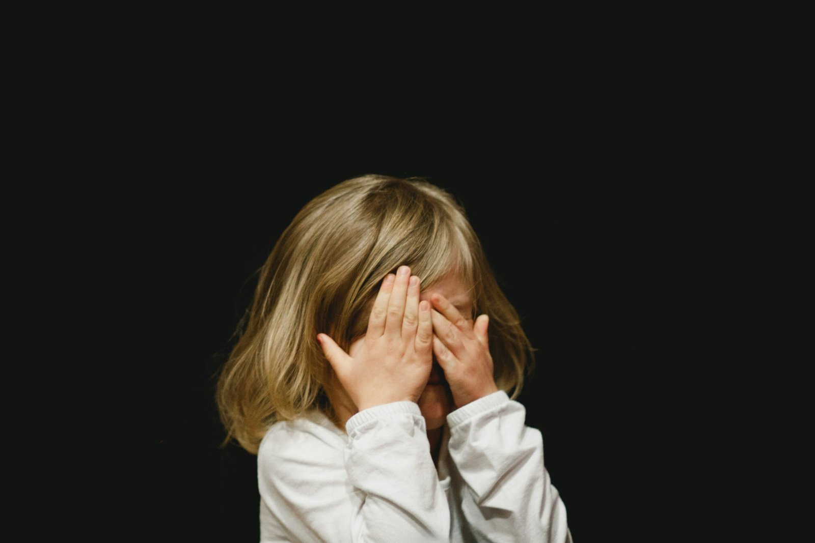 Child covering face with hands, representing sensory overload and challenges with sensory integration dysfunction.