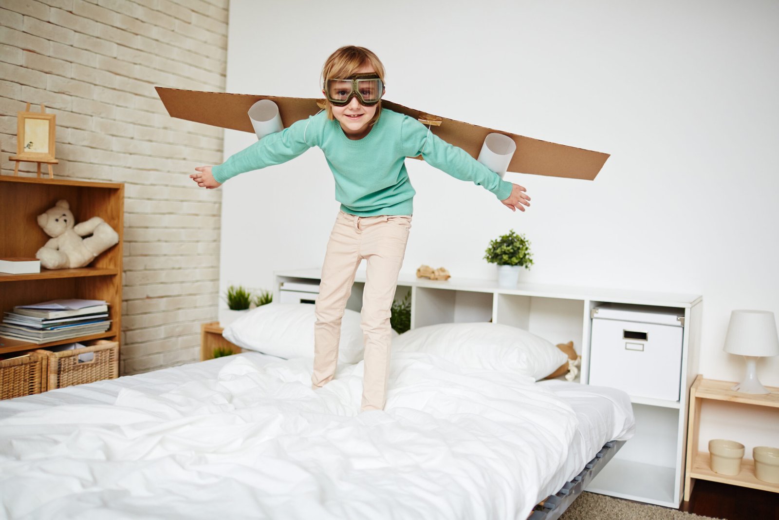 Young boy wearing a cardboard airplane costume and goggles, pretending to be a pilot, expressing creativity and imagination.