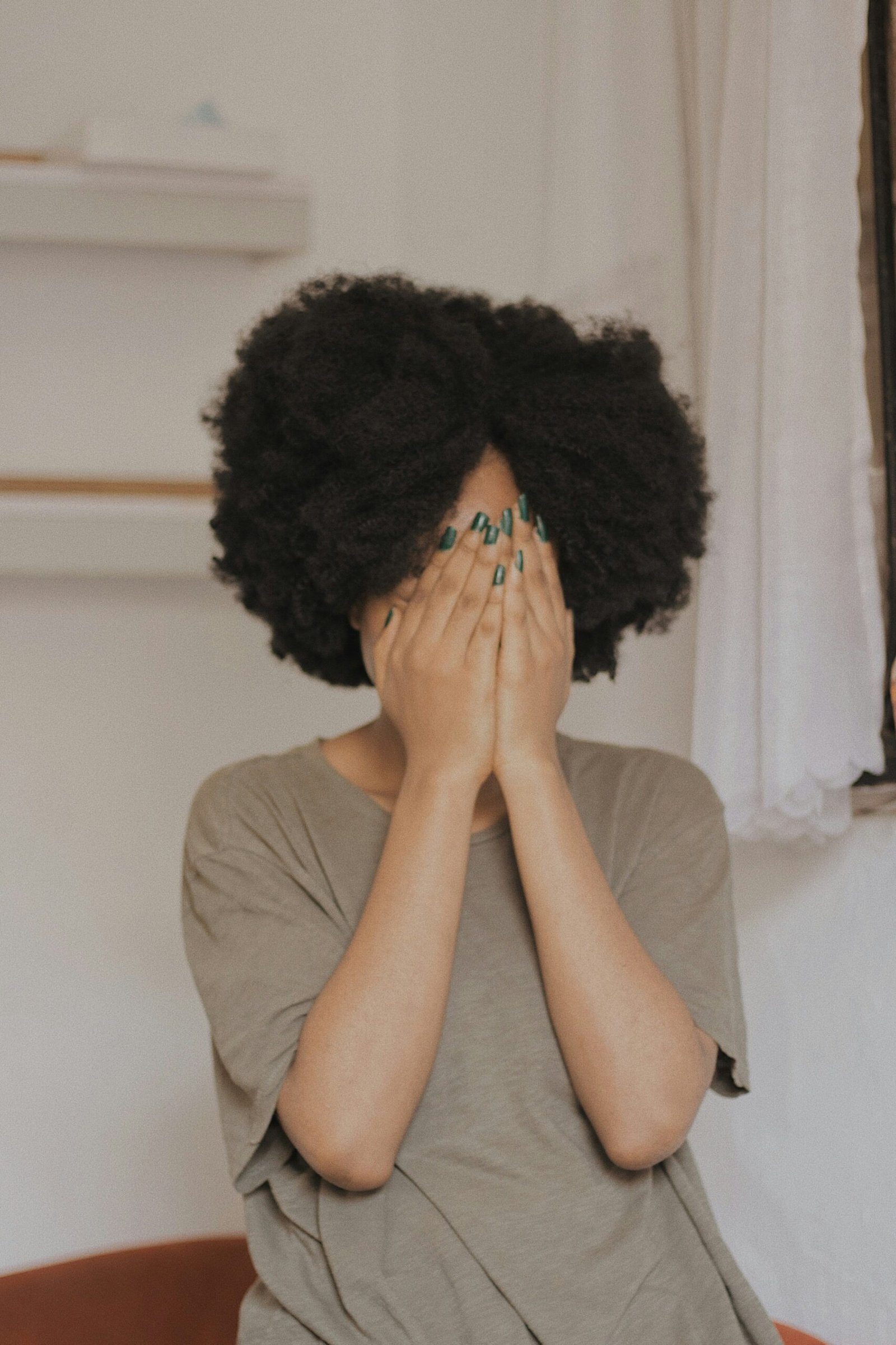 Young woman feeling shy, covering her face with both hands, symbolizing extreme shyness and social anxiety.