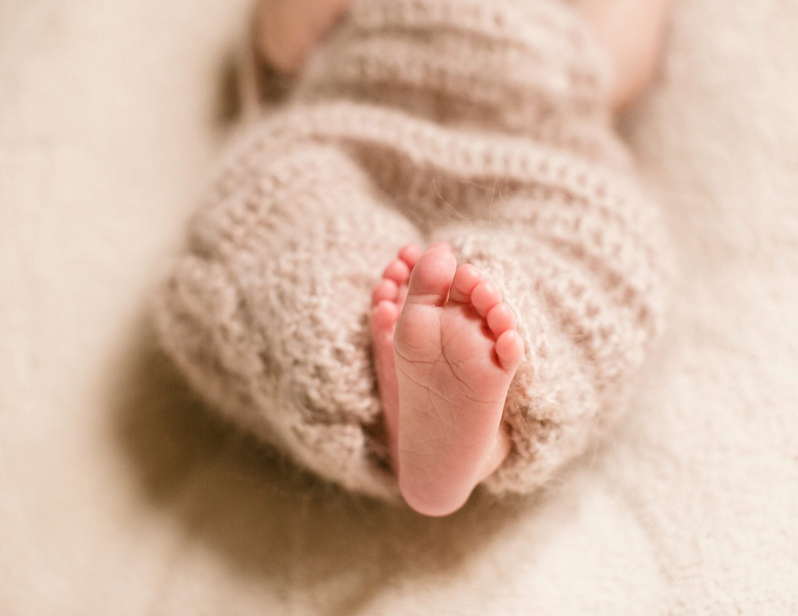 Close-up of a child's feet wrapped in a cozy wool scarf, symbolizing growth and development in early childhood.