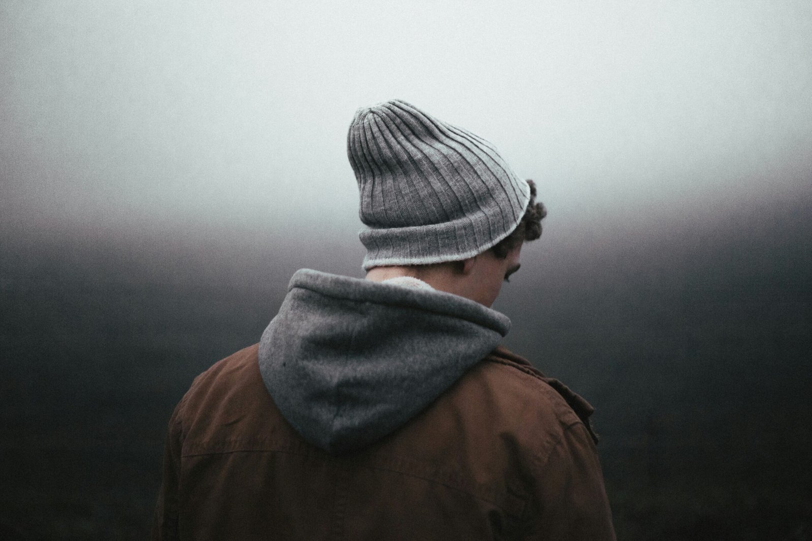 Man with a serious expression wearing a knit cap and sweater, representing focus and emotional regulation.