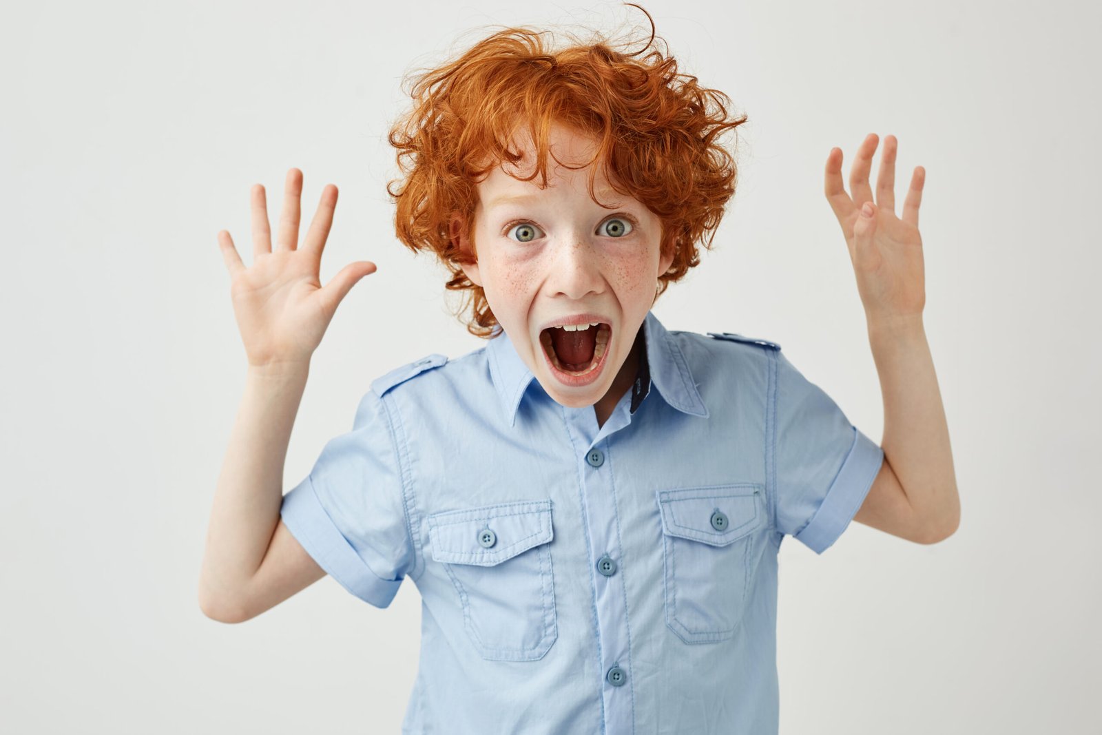 Close-up of a red-haired child screaming with arms outstretched, representing impulsive behavior in children and the need for emotional regulation.