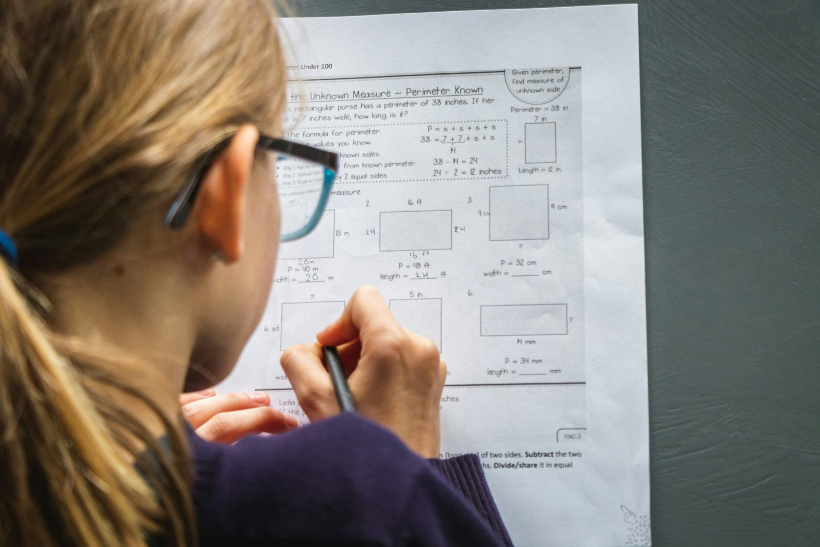 Woman concentrating with black-framed glasses and pen, symbolizing focus and brain reorganization techniques for improved attention.