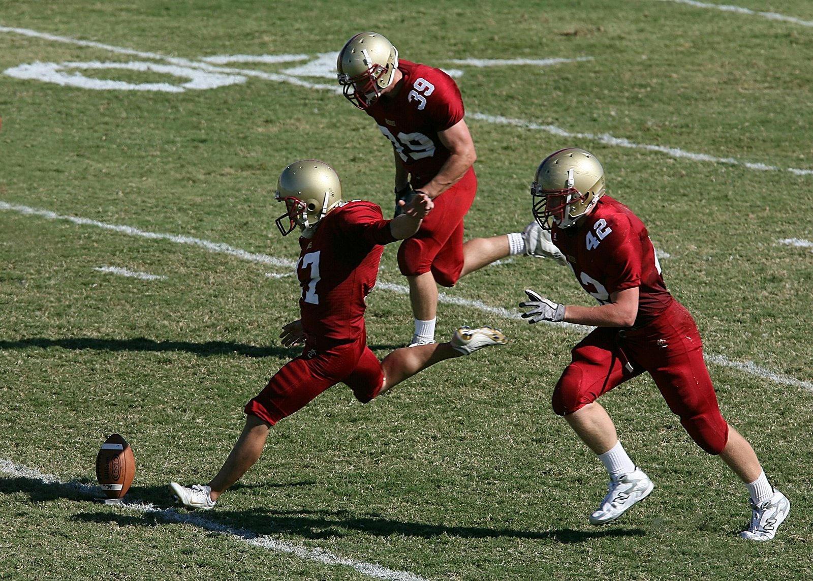 Football player kicking a ball, demonstrating muscle coordination and balance in action.