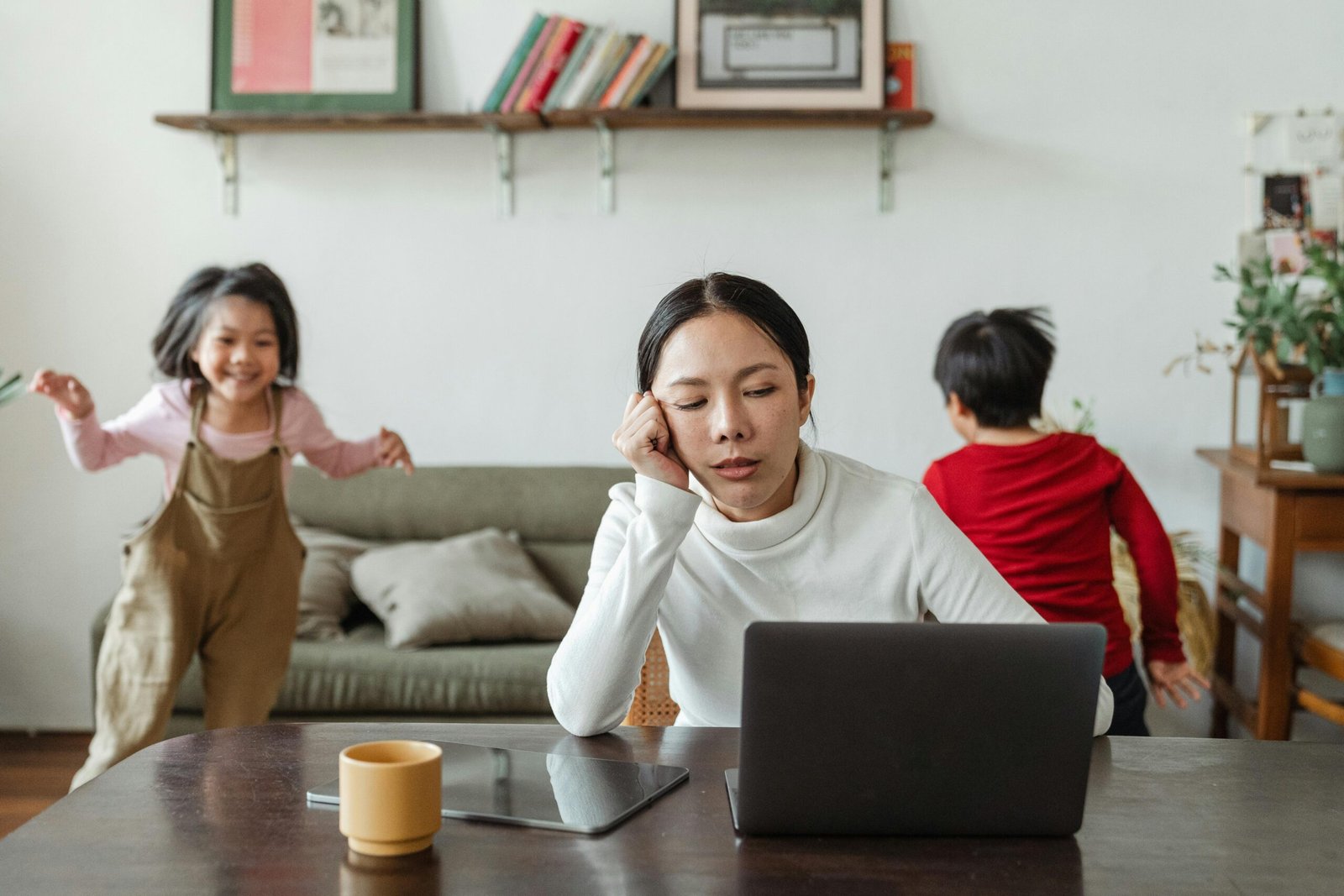 Tired mom with kids jumping around behind
