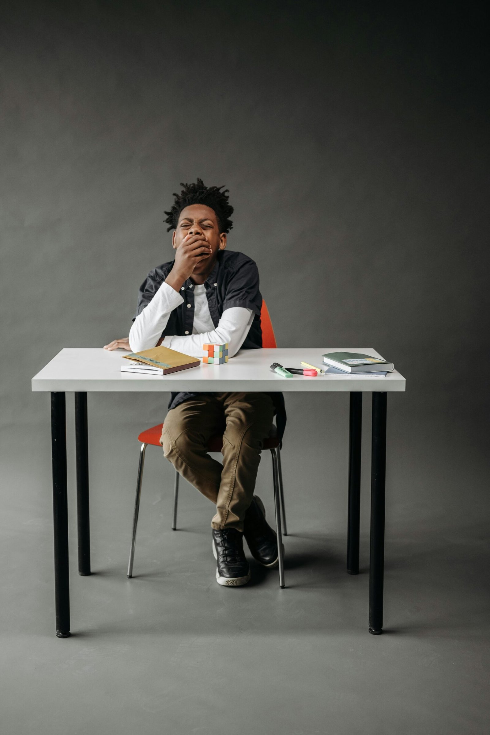 Boy yawning sitting at a desk