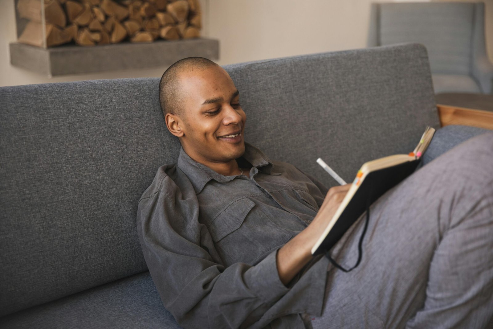 Man sitting on couch with notebook and pen writing