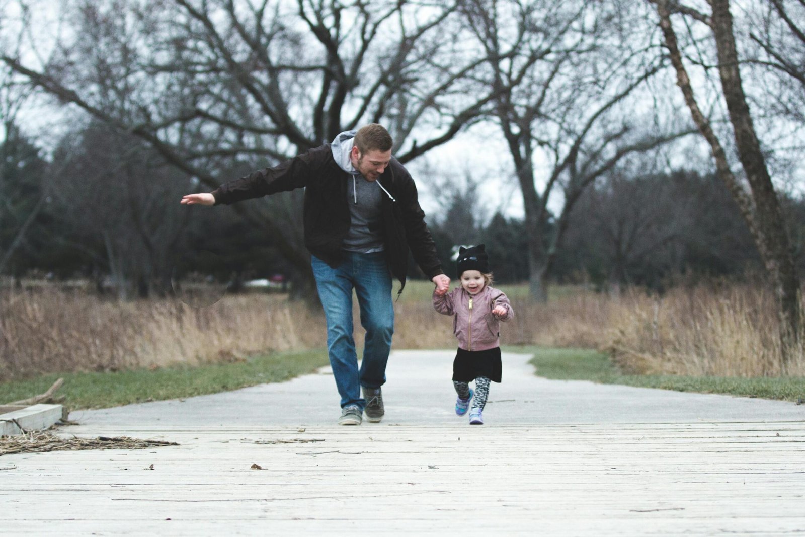 A dad and his little daughter walking on a path holding hands