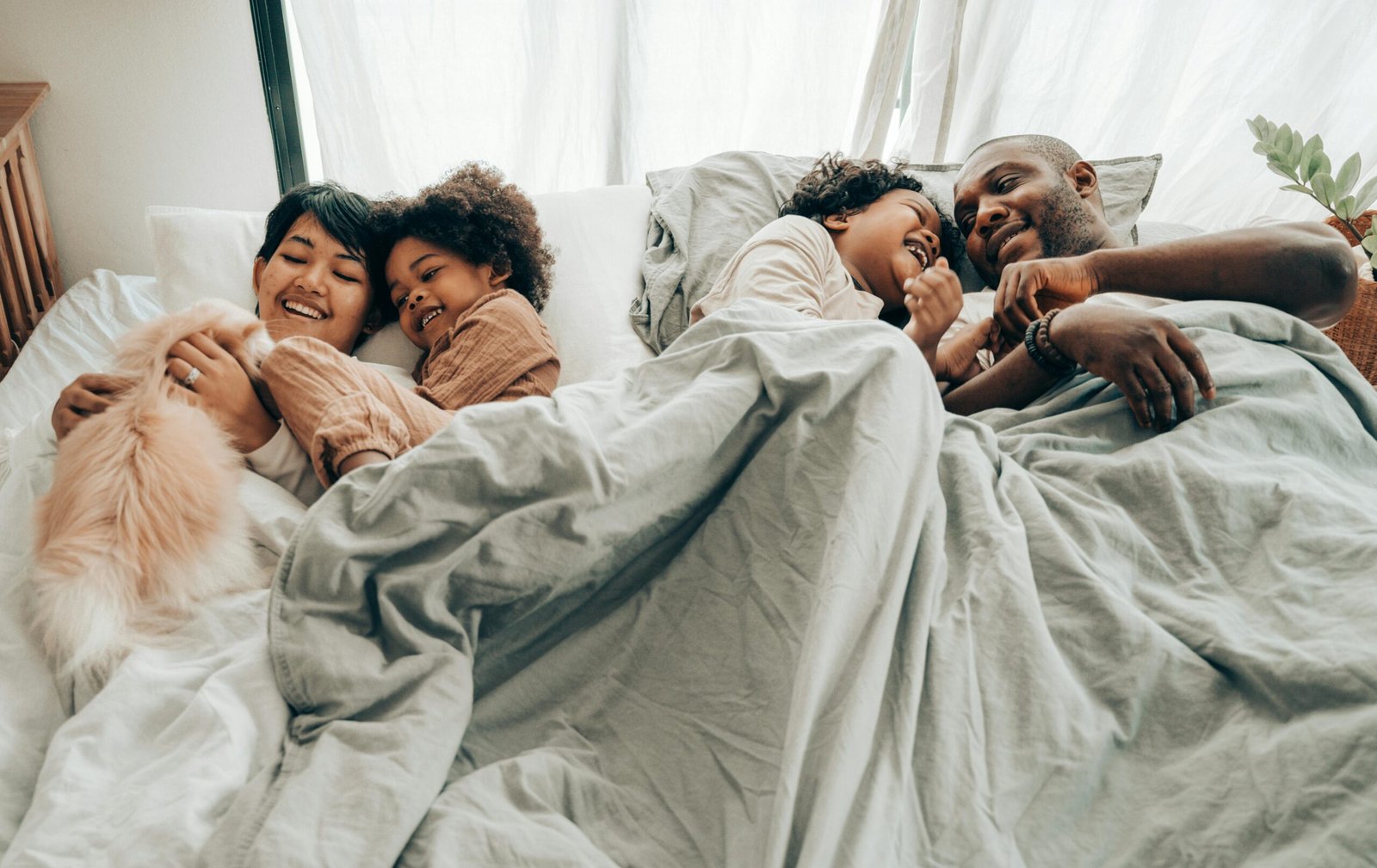 A mom, a dad, and two kids smiling in a bed